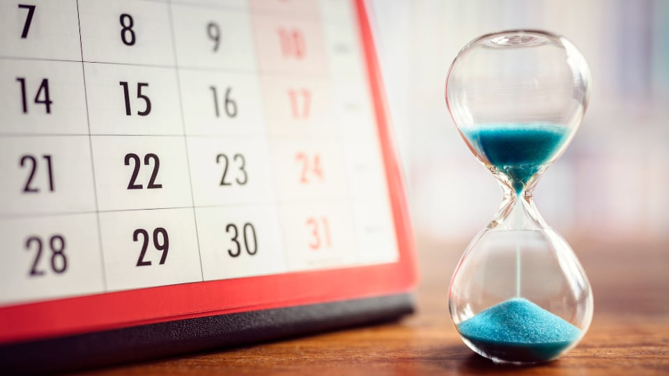 hour glass filling and calendar behind it